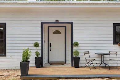View of exterior entry with a deck and metal roof