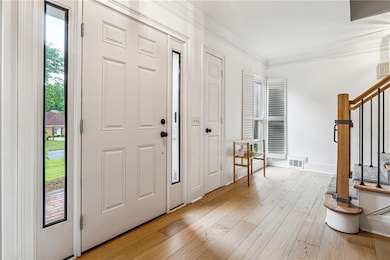 Entryway featuring stairs, ornamental molding, lig