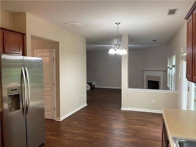 Kitchen featuring stainless steel refrigerator with ice dispenser, open floor plan, dark wood-style floors, a fireplace, and a chandelier