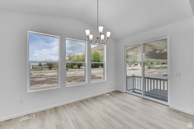 Unfurnished dining area featuring lofted ceiling, a chandelier, and light wood-style flooring