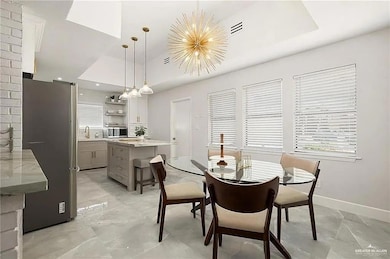 Dining space featuring a raised ceiling, a chandelier, and light marble finish flooring