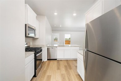 The heart of the home features sleek stainless steel appliances, white shaker cabinetry, and granite countertops—ideal for both everyday meals and gourmet creations.