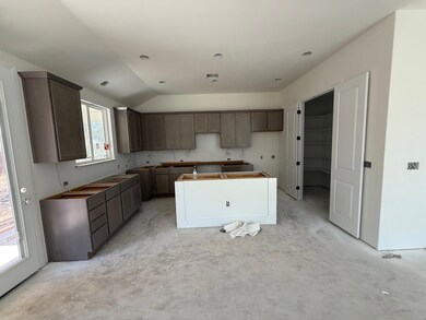 Kitchen with a kitchen island, vaulted ceiling, and dark brown cabinets