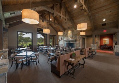 Carpeted living area featuring high vaulted ceiling, a wooden ceiling with exposed beams, an outdoor stone fireplace, and a wainscoted wall