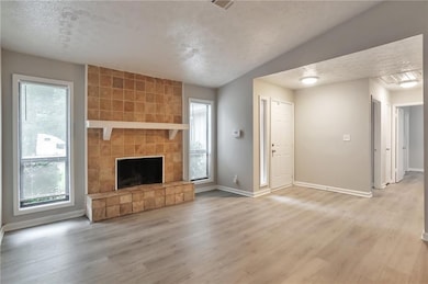 Unfurnished living room featuring a textured ceiling, light wood-type flooring, and a fireplace