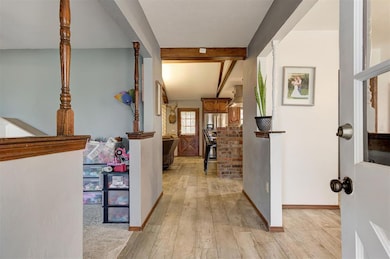 Hallway featuring beamed ceiling and light hardwoo