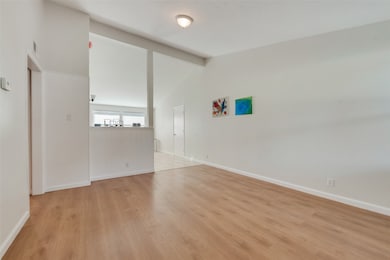 Empty room with light wood-style floors, beam ceiling, and high vaulted ceiling