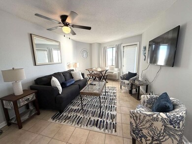 Living area with light tile patterned flooring, a textured ceiling, a textured wall, and a ceiling fan