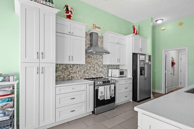 Kitchen with white cabinets, wall chimney range ho