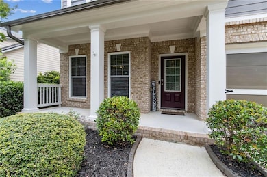 View of exterior entry with covered porch and brick siding
