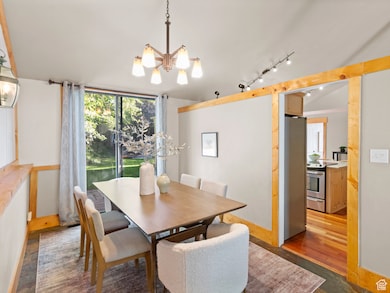 Dining area featuring dark wood-type flooring, a chandelier, and rail lighting
