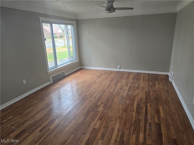 Unfurnished room with a textured ceiling, dark wood-style floors, crown molding, and a ceiling fan