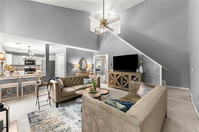 Living area featuring light colored carpet, a high ceiling, and a chandelier