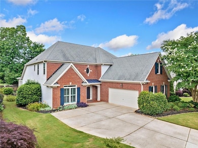 Traditional home with brick siding, a garage, a shingled roof, driveway, and a front yard