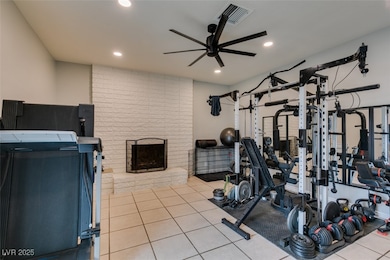 Exercise room with a ceiling fan, recessed lighting, and a fireplace