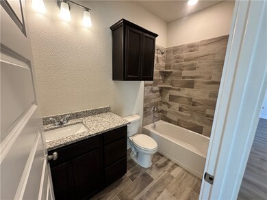 Full bath with a textured wall, vanity, bathtub / shower combination, and wood tiled floors