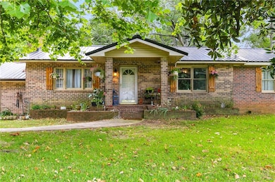 Single story home with a metal roof, a front yard, and brick siding