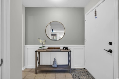 Foyer with wainscoting, light tile patterned flooring, a decorative wall, a ceiling fan, and a textured ceiling