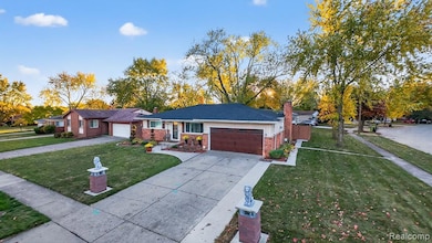 Ranch-style home with driveway, brick siding, an attached garage, and a chimney