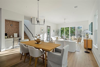 Dining area with wine cooler, bar area, stairs, light wood finished floors, and a chandelier