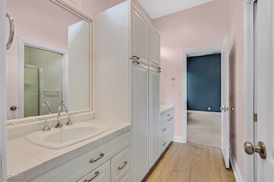 Bathroom with two vanities, light wood-type flooring, and a stall shower