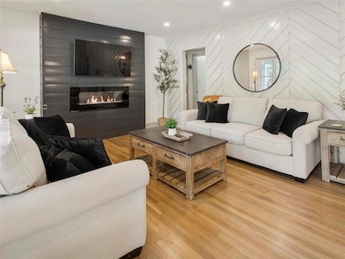 Living room with a large fireplace, light wood-type flooring, and recessed lighting
