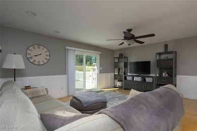 Living room with light wood-style flooring, a wainscoted wall, a decorative wall, a ceiling fan, and recessed lighting