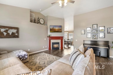 Living room with dark wood-style floors, a tiled fireplace, high vaulted ceiling, a chandelier, and a ceiling fan