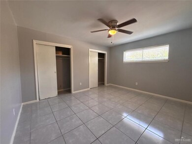 Unfurnished bedroom with tile patterned flooring, baseboards, multiple closets, and a ceiling fan