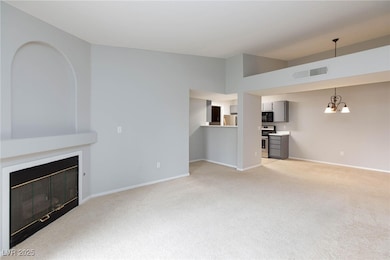 Unfurnished living room featuring light carpet, a glass covered fireplace, and a chandelier