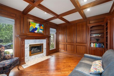Living room featuring cherrywood, built in shelves, wood flooring, coffered ceiling, and a fireplace