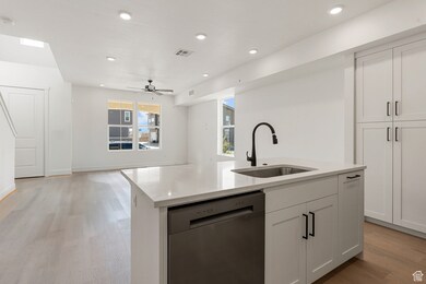 Kitchen featuring dishwasher, light wood finished floors, light stone countertops, white cabinets, and recessed lighting