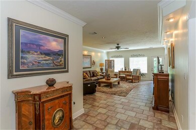 View standing inside the entry/foyer, looking toward the extra large living room/den/great room.  The tile flooring is reminiscent of cobblestone and is laid on a brick lay design for added character. There is an abundance of crown molding in home.