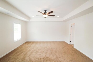 Unfurnished room featuring light colored carpet, ceiling fan, a raised ceiling, and recessed lighting