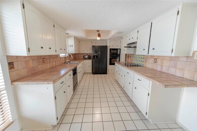 Kitchen with black appliances, tile counters, und