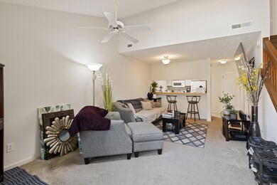 Carpeted living room featuring ceiling fan and a h