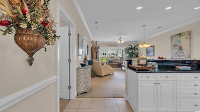 Kitchen with light carpet, light tile patterned floors, dark countertops, crown molding, and white cabinets