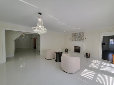 Great room living room featuring ornamental molding, a high end fireplace, a chandelier, and baseboards