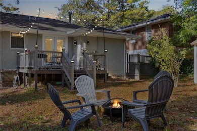 Back of house at dusk with brick siding, a wooden deck, and a fire pit