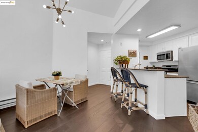 Kitchen with white cabinetry, dark stone countertops, appliances with stainless steel finishes, dark wood-style flooring, and a breakfast bar