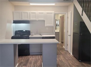 Kitchen with white cabinets, black appliances, sink, and dark wood-type flooring
