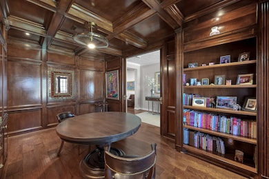 This richly appointed study features stunning wood paneling, built-in bookshelves, and a coffered ceiling that exudes timeless elegance. The warm tones and detailed craftsmanship create an inviting space ideal for work, reading, or conversation. Perfectly positioned off the entryway, it offers both sophistication and functionality.