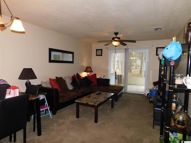 Carpeted living area with a ceiling fan and a textured ceiling