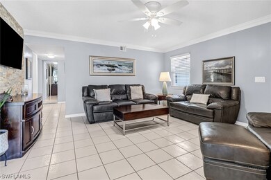 Tiled living room featuring ceiling fan and crown