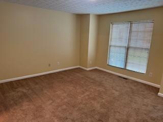 Spare room with dark colored carpet