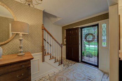 Foyer entrance with crown molding and a chandelier