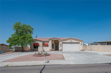 View of front facade featuring driveway, stucco siding, a tile roof, and an attached garage
