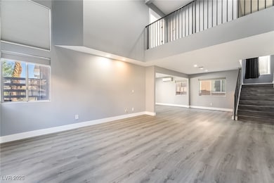 Unfurnished living room with wood finished floors, a towering ceiling, stairway, recessed lighting, and a wall mounted air conditioner
