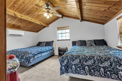 Carpeted bedroom with a wall mounted AC, wooden c