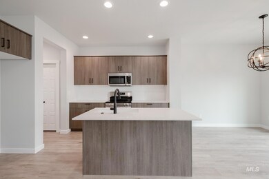 Kitchen with hanging light fixtures, stainless steel appliances, a kitchen island with sink, light wood-style flooring, and recessed lighting
